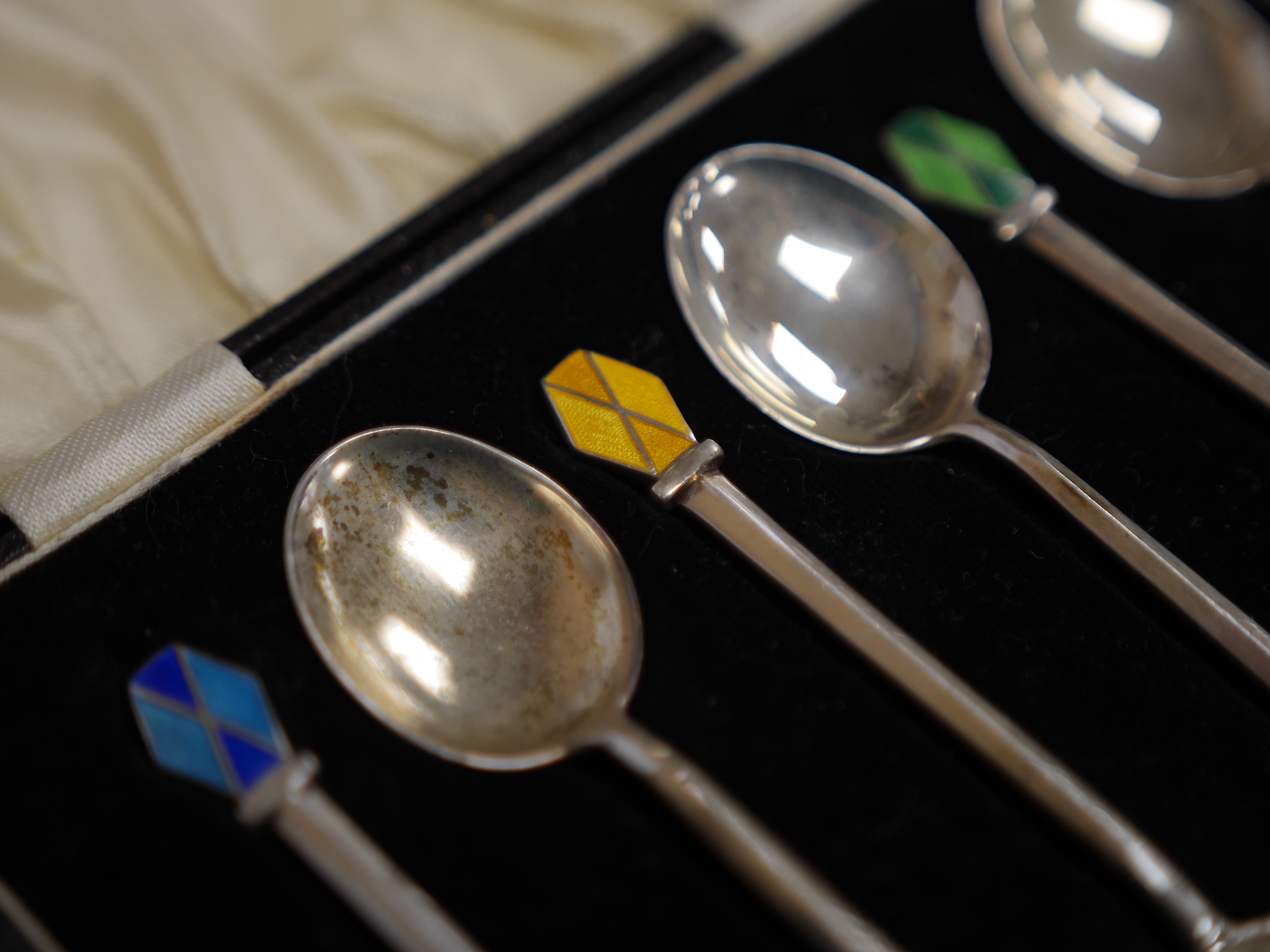 A 1980's Georg Jensen silver handled stainless steel Acorn pattern salad server, 23.8cm, together with a cased set of six Art Deco silver and polychrome enamel coffee spoons, W H Haseler Ltd, Birmingham, 1938. Condition